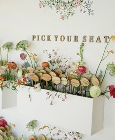 a display with flowers and wine corks on the wall next to a sign that says pick your seat