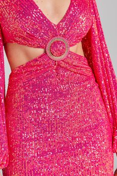 a woman wearing a bright pink dress with cut outs and sequins on it