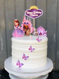 a white cake with purple frosting and princess characters on top is sitting on a plate