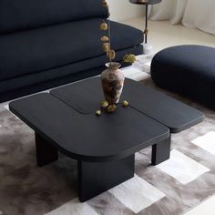 a living room with black couches and a coffee table in the middle on carpeted flooring