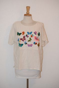 "Sweet little vintage top will have your ready for dancing and having fun in the summer breeze. Creamy gauzy muslin peasant ethnic summer top / blouse with short fluttery sleeves and embroidered colorful butterflies was made in Guatemala.  So sweet for any summer occasion.  Free of rips, stains and odor. Women's oversize medium to large Back of neck to bottom of blouse:  25\" Shoulder to shoulder at back:  22\" Top of sleeve to bottom hem:  7\" Armpit to armpit:  24\" Under arm seam:  17\" Side to side at waist:  21 1/2\" Side to side at bottom:  22\" For a variety of vintage goodies, check out my shop @: https://www.etsy.com/shop/RagandBonesFinds For a unique pillow fashioned from my treasure trove of vintage fabrics, visit my shop @: https://www.etsy.com/shop/VintagePulledThreads" Spring Crew Neck Blouse For Beach, Summer Crew Neck Blouse With Floral Embroidery, Summer Beach Blouse With Crew Neck, Summer Crew Neck Blouse For Beach, Summer Crew Neck Blouse For The Beach, Beach Peasant Top With Boho Collar, Spring Beach Blouse With Boho Collar, Beach Style Peasant Top With Boho Collar, Casual Embroidered Top With Boho Collar For Spring