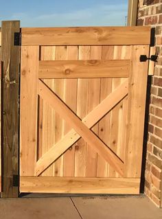 an open wooden gate on the side of a brick building