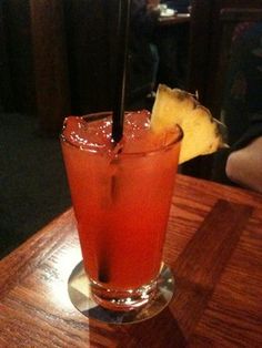 a tall glass filled with liquid on top of a wooden table