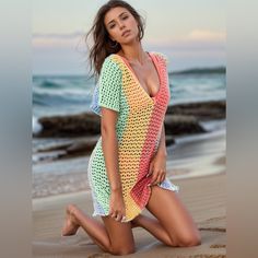 a woman in a colorful crochet cover up on the beach posing for a photo