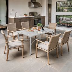 an outdoor dining table with six chairs in front of a large open kitchen and living room