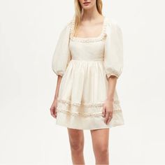 A New Design For Summer, The Daya Dress Is A Mini That Can Be Worn In Many Moods. Made In A Crisp Cotton Poplin, It Has A Flattering Darted Bust And A Full, Flowy Skirt. A Unique Pleated Detail Around The Neck And Towards The Hem Adds A Special Flourish That’s Elegant Without Being Over The Top. 100% Cotton Empire Waist. Hand Wash Cold. Do Not Bleach. Line Dry. Medium Iron. Or Dry Clean. Imported Model Is 5’10” And Is Wearing A Size 2. Feminine Cream Mini Dress With Square Neck, Elegant Puff Sleeve Dress With Lace Trim For Spring, Cream Square Neck Dress With Lace Trim, Cream Lace Trim Square Neck Dress, Cream Lace Trim Dress With Square Neck, Beige Puff Sleeve Mini Dress For Brunch, Beige Square Neck Dress For Daywear, Feminine Cream Puff Sleeve Dress With Square Neck, White Puff Sleeve Dress With Lace Trim