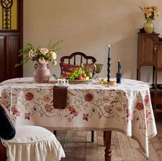 a table with flowers and fruit on it in a dining room area next to a chair