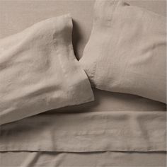 two pillows are laying next to each other on a bed with sheets and pillow cases