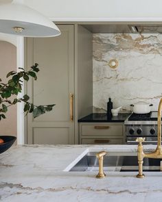 a kitchen with marble counter tops and gold faucets