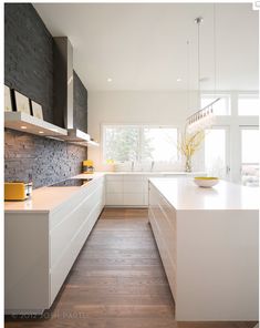 a kitchen with white cabinets and wood flooring on the walls, along with a wooden floor