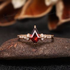 a red and white diamond ring sitting on top of a rock