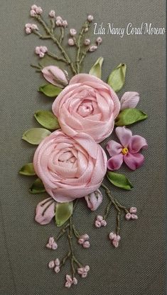 some pink flowers and green leaves on a gray surface