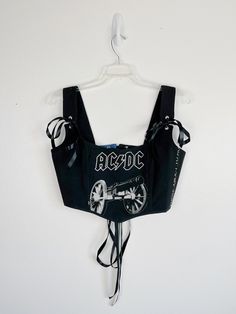 Pay homage to rock legends with this edgy corset top, meticulously crafted from a high-quality black shirt adorned with the legendary AC/DC logo across the front. Handmade with passion and attention to detail, each corset top captures the electrifying energy of the iconic band, making it the perfect choice for music enthusiasts and fashion rebels alike. 👚 Material: Crafted from premium black shirt fabric, our corset top offers both comfort and style. The bold AC/DC logo adds a touch of rock 'n' roll attitude to this versatile piece. 🎸 Design: Stand out from the crowd with our exclusive AC/DC corset top. Whether you're heading to a concert, hitting the town with friends, or simply want to unleash your inner rock star, the iconic logo and flattering silhouette of the corset style create a Rock And Roll Clothes, Rhinestone Corset Top, Rock N Roll Fashion, Rhinestone Corset, Acdc Band, Acdc Crop Top, Acdc Merch, Korsett Top, Ac Dc Shirt