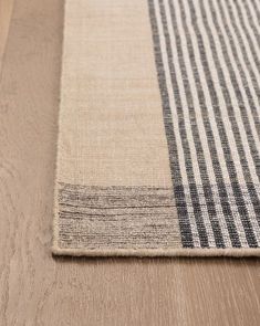 a beige and black rug on top of a wooden floor next to a wood floor