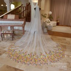 a wedding veil is draped over a dress on the floor in front of a grand piano