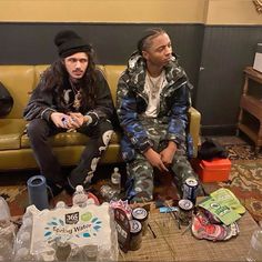 two young men sitting on a couch with bottled water and sodas all around them