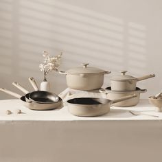 an assortment of pots and pans sitting on a table with utensils in front of them