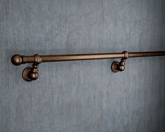 an old fashioned metal curtain rod with two knobs on the top and bottom, against a gray wall