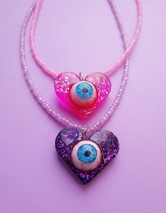 "Fashionable and stylish hippie-style epoxy resin necklace for the most daring and mysterious people. A new large heart-style necklace in various bright colors with sequins will be the best gift for your friends, family or yourself. What distinguishes this product from most conventional jewelry is the mysterious realistic human eye. The eye is completely hand-painted and has no more analogs in the whole world! Do you want to make an unforgettable impression on people? Then the scary and cute necklaces with a \"Heart with an eye\" pendant are just for you. Epoxy resin is a stable and reliable material that does not change over time, does not break, and always looks spectacular. The base of the earrings in the form of a ring with a latch is made of high-quality surgical steel. To make your j Funny Heart Necklace, Creepy Eye Necklace, Heart Eye Necklace Clay, Trippy Necklaces, Handmade Resin Jewelry, Heart-shaped Beaded Necklace For Parties, Handmade Heart Pendant Necklace For Party, Heart Charm Necklace For Festival, Heart Charm Necklace For Festivals