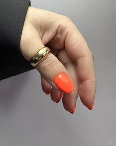 a woman's hand with an orange manicure and gold ring on her finger