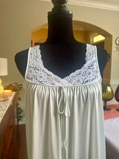 A lovely nightgown with lace trim on the bodice.  The color is somewhere between a very pale blue and light pearl gray.  Lace neckline on the front with a decorative tie at the bustling.  In good vintage condition with no rips or stains.  The bust measures 18 inches from armpit to armpit, laying flat.  55 inches from shoulder to hem, ideal for someone on the taller side.  100% nylon. Size medium Feminine Sleeveless Delicate Lace Sleepwear, Feminine Delicate Lace Sleeveless Sleepwear, Summer Sleeveless Nightgown With Delicate Lace, Delicate Lace Sleeveless Dress For Loungewear, Sleeveless Nightgown With Delicate Lace For Loungewear, Summer Sleeveless Delicate Lace Nightgown, Sleeveless Delicate Lace Nightgown For Loungewear, Sleeveless Delicate Lace Summer Nightgown, Sleeveless Lace Camisole For Loungewear