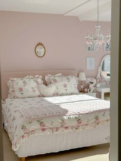 a bedroom with pink walls and white bedding, chandelier hanging from the ceiling