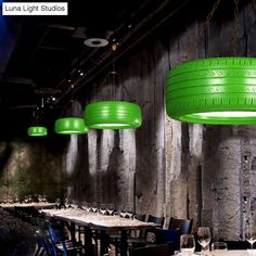 an image of a restaurant setting with green tires hanging from the ceiling and tables in front of them