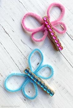 two pink and blue hair clips sitting on top of a white wooden table next to each other