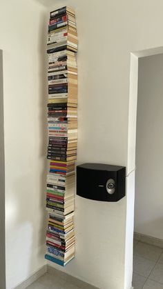 a stack of books sitting next to a wall mounted speaker