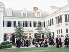 a group of people standing in front of a large white building with lots of windows