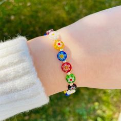 a person's arm with a bracelet made out of glass beads and flowers on it