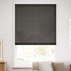 a living room with a white couch and window covered in black blind shades on the windowsill