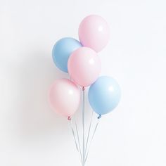 a bunch of pastel colored balloons floating in the air on a white wall background