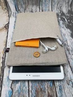 an ipad case with headphones and earbuds in it sitting on top of a tablet