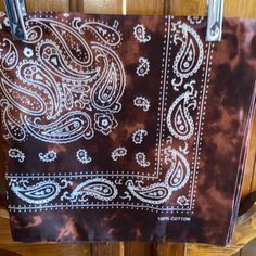 a brown and white bandana hanging on a wooden door with metal hooks in front of it