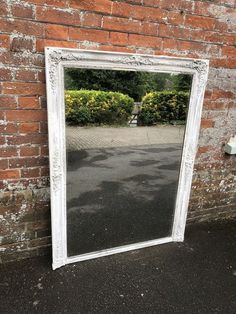 an old white mirror leaning against a brick wall