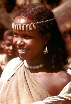 a woman wearing a head piece with beads on it's head and smiling at the camera