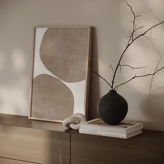 a black vase sitting on top of a wooden dresser next to a framed photo and some books