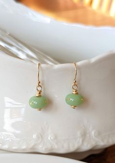 Using the same glass as the jade chrysalis, I've created a set of matching earrings. A refined, elegant companion to your Monarch chrysalis replica necklace in the same jade colored glass. Four 24k gold dots are perfectly placed on the bead. The findings are 14k gold-filled. I'm so happy to finally be offering these. Many people opt for the complex miniature chrysalis earrings, but it's lovely to be able to offer a simple, inexpensive option as well. Please note, if purchased with another piece, Elegant Light Green Earrings As Gift, Elegant Light Green Earrings For Gift, Elegant Green Czech Glass Earrings, Jade Wire Wrapped Earrings For Gifts, Wire Wrapped Jade Earrings As Gift, Gold Hypoallergenic Jade Earrings, Hypoallergenic Gold Jade Earrings, Monarch Chrysalis, 22nd Anniversary