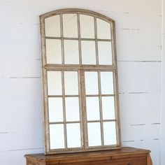 an old wooden dresser with a mirror on it's top and drawers below, against a white wall