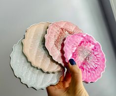 three pink and white plates in the shape of flower petals are being held by a woman's hand