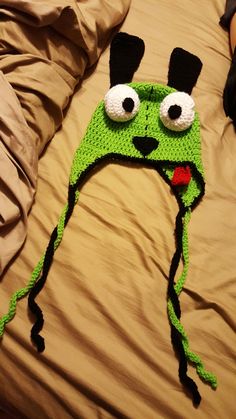 a crocheted hat that looks like a frog with big eyes and black ears