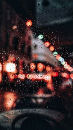 blurry image of lights and street signs through a rain - covered window with the word qubeq on it