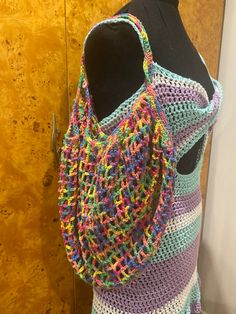 a multicolored crocheted bag on display in front of a wooden door