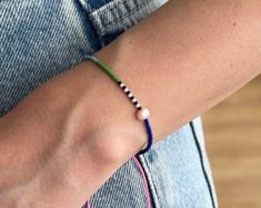 a close up of a person wearing a bracelet with beads on their wrist and the other hand