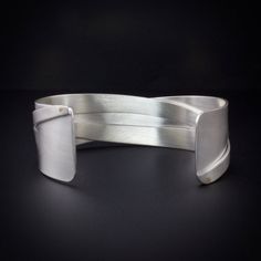 Sterling silver woven cuff bracelet that has 18K Gold rivets.  A unique contemporary cuff design where the cuff has been sawed, woven and riveted to give it a unique look.  The surface can be brushed matte or have a shiny polished finish. The cuff is made to order for your size wrist see drop down menu for sizes and finish.   Photos 1 thru 4 show the cuff in a matte finish and photo 5 shows the cuff in a polished shiny finish.  The cuff bracelet is 0875 inch (22.23) wide at the ends and 0.625... Modern Twist Polished Bangle Cuff Bracelet, Modern Handmade Cuff Bangle, Unique Cuff Bracelet For Formal Occasions, Modern Twist Cuff Bracelet Bangle For Formal Occasions, Modern Twist Bangle Cuff Bracelet For Formal Occasions, Modern Handmade Cuff Jewelry, Modern Handmade Cuff Bracelets, Modernist Cuff Bangle Bracelet With Oyster Design, Modernist Cuff Bangle With Oyster Bracelet