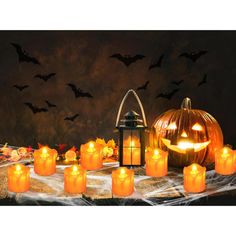 pumpkins and candles on a table with bats in the background