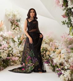 a woman standing in front of flowers wearing a black dress