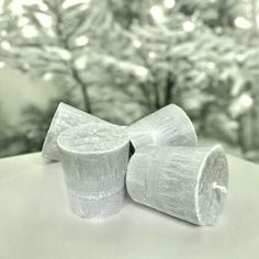 two rolls of toilet paper sitting on top of a white table next to a tree