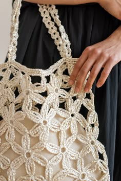 a close up of a person holding a handbag with crochet on it